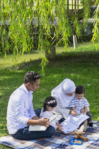 People sitting on grassland against plants