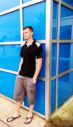 Handsome man standing against blue glass building