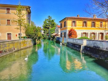 Canal by swimming pool in building against clear blue sky