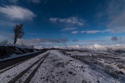 Road amidst snowcapped landscape against sky