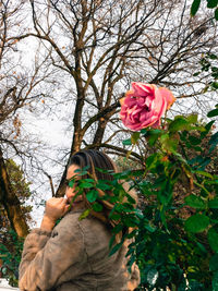 Close-up of hand holding rose against trees
