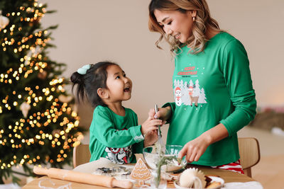 Funny asian mixed race mom and daughter are preparing cookies for the christmas holiday at home