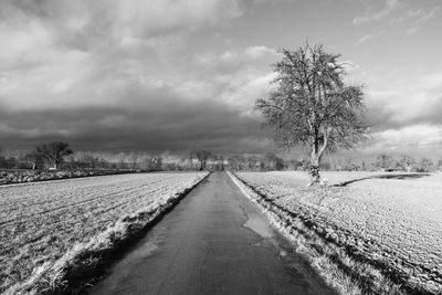 Empty road along snow covered landscape