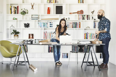 Architects working at table against bookshelf in home office