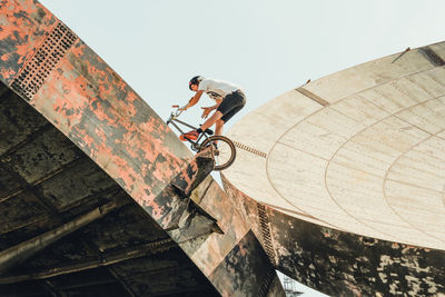 Low angle view of man riding bicycle on satellite dish