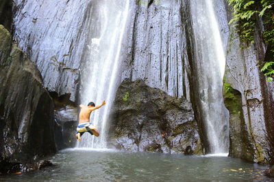 Full length of woman standing in waterfall