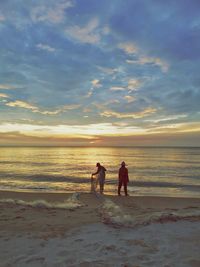 People on beach against sky during sunset