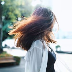 Woman tossing hair while standing outdoors