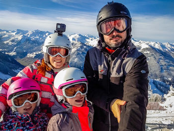 Smiling family standing against sky against mountain during winter