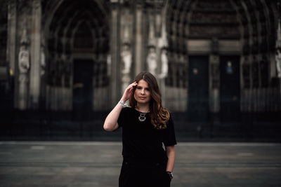 Young woman looking down while standing against built structure