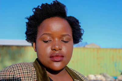 Close-up of woman with short hair against blue sky