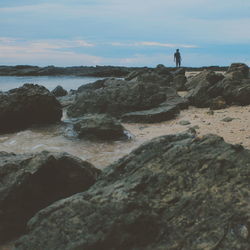 Man standing on rock at seaside