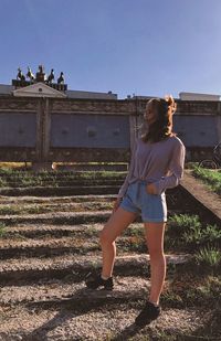 Young woman standing on steps against historical building