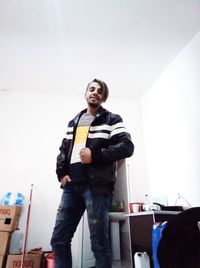 Portrait of young man standing against wall