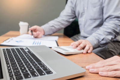 Midsection of man using laptop on table
