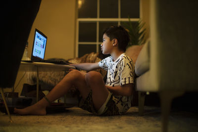 A half japanese boy uses a laptop in the living room