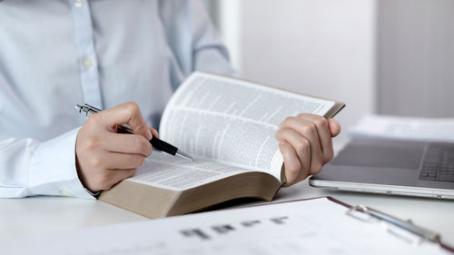 Midsection of woman writing in book