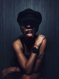 Portrait of young man wearing hat against wall