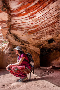 Side view of woman sitting on rock