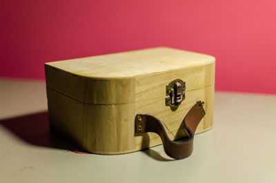 Close-up of wooden container on table against pink background