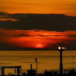 Illuminated street lights against orange sky