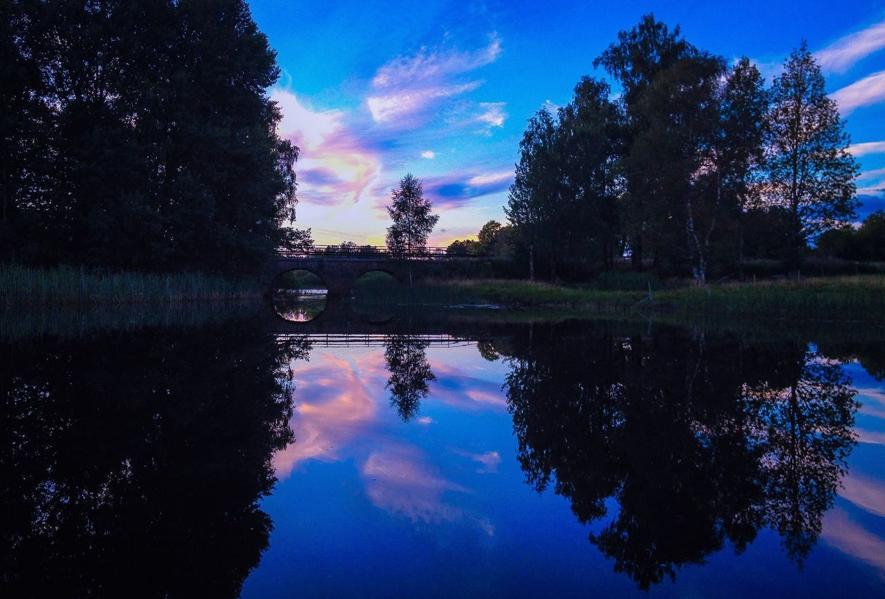 reflection, water, tree, tranquility, lake, tranquil scene, sky, silhouette, scenics, sunset, beauty in nature, standing water, waterfront, nature, calm, idyllic, dusk, blue, cloud - sky, cloud