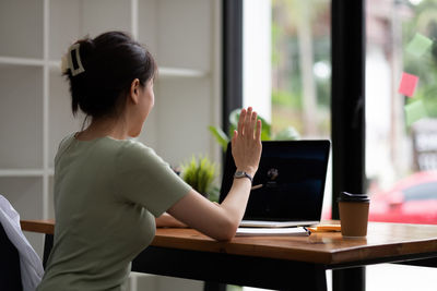 Woman using phone while sitting on table