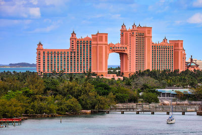 Buildings by river against cloudy sky