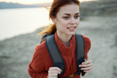 Portrait of smiling young woman standing at beach