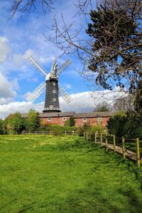 Traditional windmill on field against sky