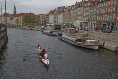 Boats in river against buildings in city
