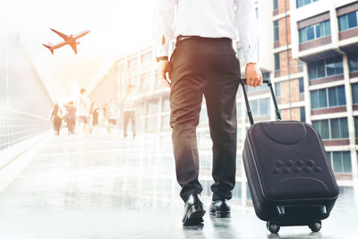 Digital composite image of businessman with luggage walking airport against buildings