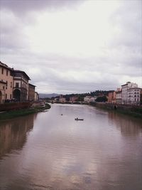 Buildings by river against sky in city