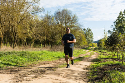 Full length portrait of man standing on grass against trees