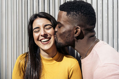 Man kissing woman against wall