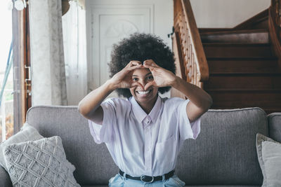 Woman making heart gesture at home