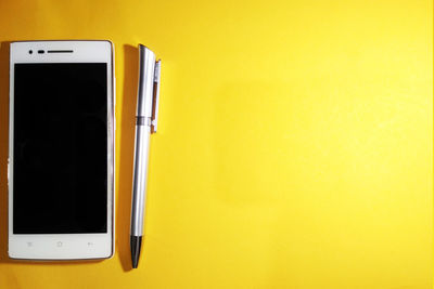 Close-up of smart phone against yellow background