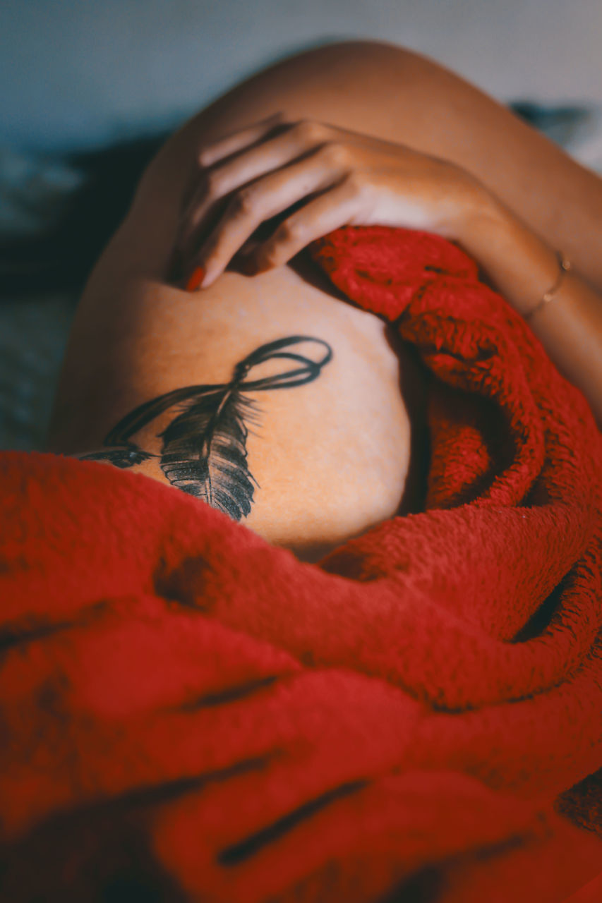 CLOSE-UP OF YOUNG WOMAN LYING DOWN ON RED BLANKET