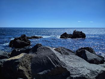 Scenic view of rocks in sea against blue sky