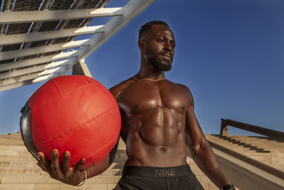 Full length of shirtless man standing against sky