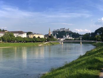 Scenic view of river by buildings against sky