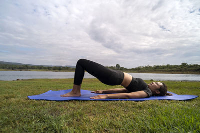 Low section of woman sitting on field against sky