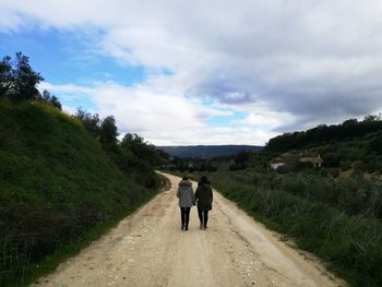 Rear view of man walking on road against sky