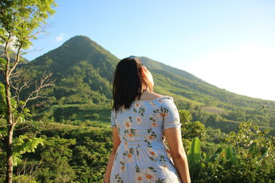 Rear view of woman standing against mountains