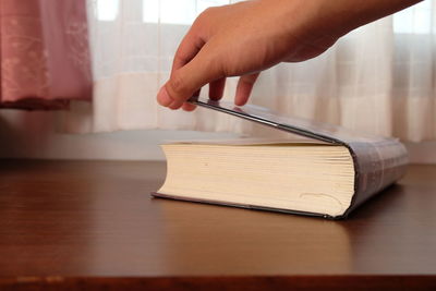 Close-up of hand holding book on table