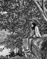 Man sitting on tree trunk against plants