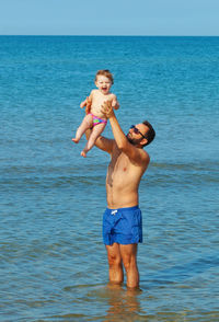 Full length of father and son on sea