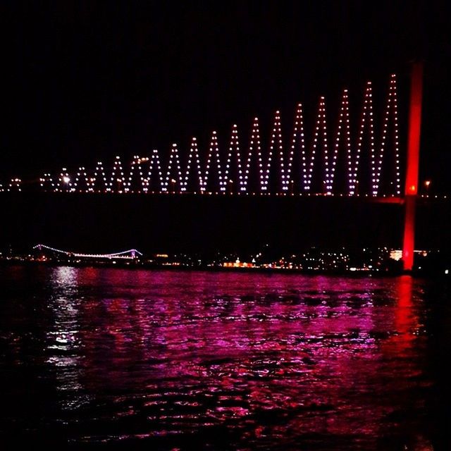 illuminated, night, water, waterfront, architecture, built structure, reflection, building exterior, river, city, bridge - man made structure, rippled, long exposure, sky, connection, sea, outdoors, no people, multi colored, travel destinations