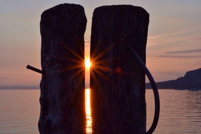 Wooden posts against lake garda during sunset
