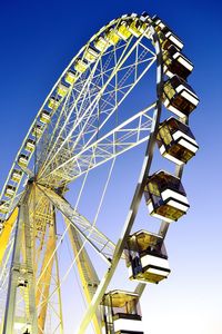 Low angle view of ferris wheel against clear blue sky